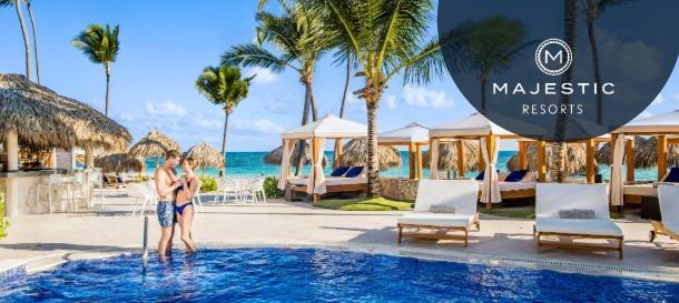 Majestic Resorts beachfront pool with couple in water, palm trees and oceanfront cabanas