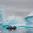 Small boat of travelers observing icebergs in Antarctica