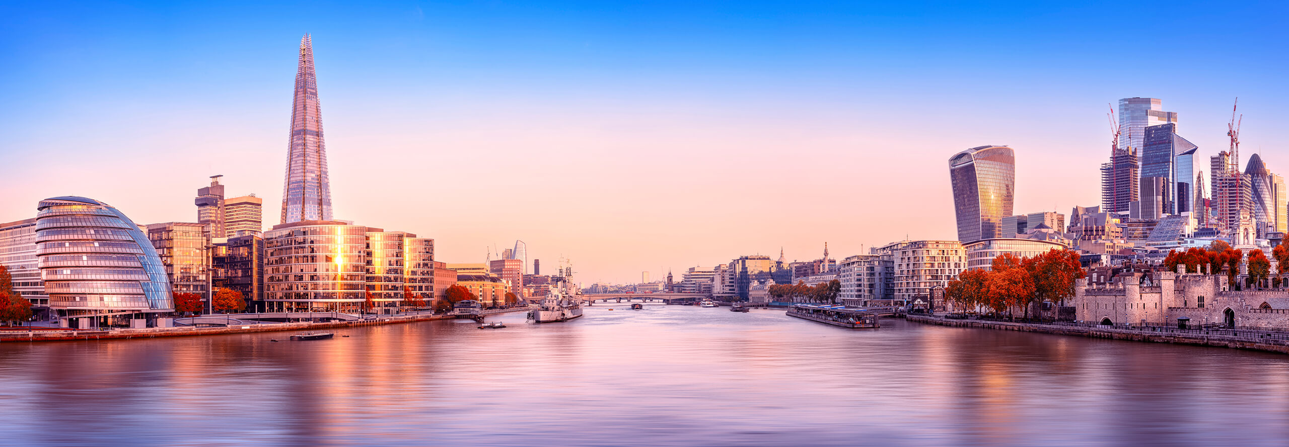 The skyline of London is visible in the background against water, showcasing iconic buildings and structures