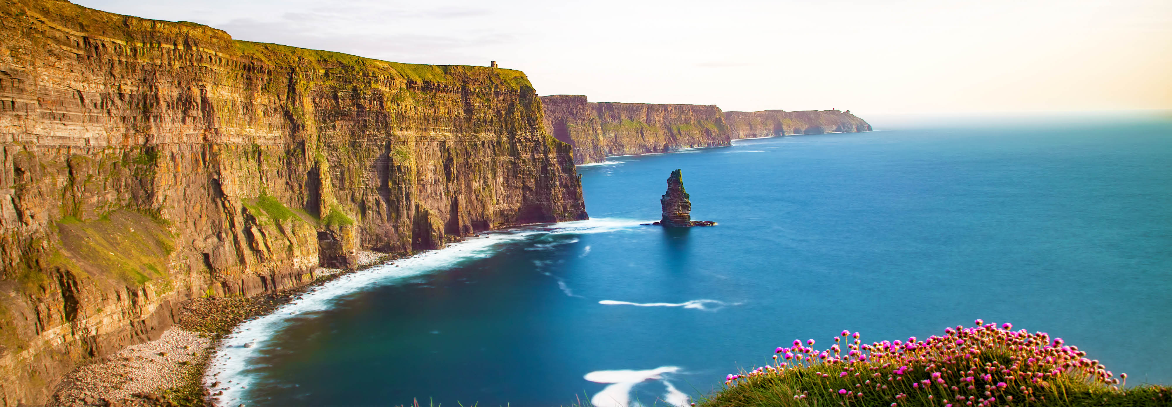 Cliffs of Moher towering over the Atlantic Ocean in County Clare, Ireland, showcasing dramatic rock formations and lush greenery