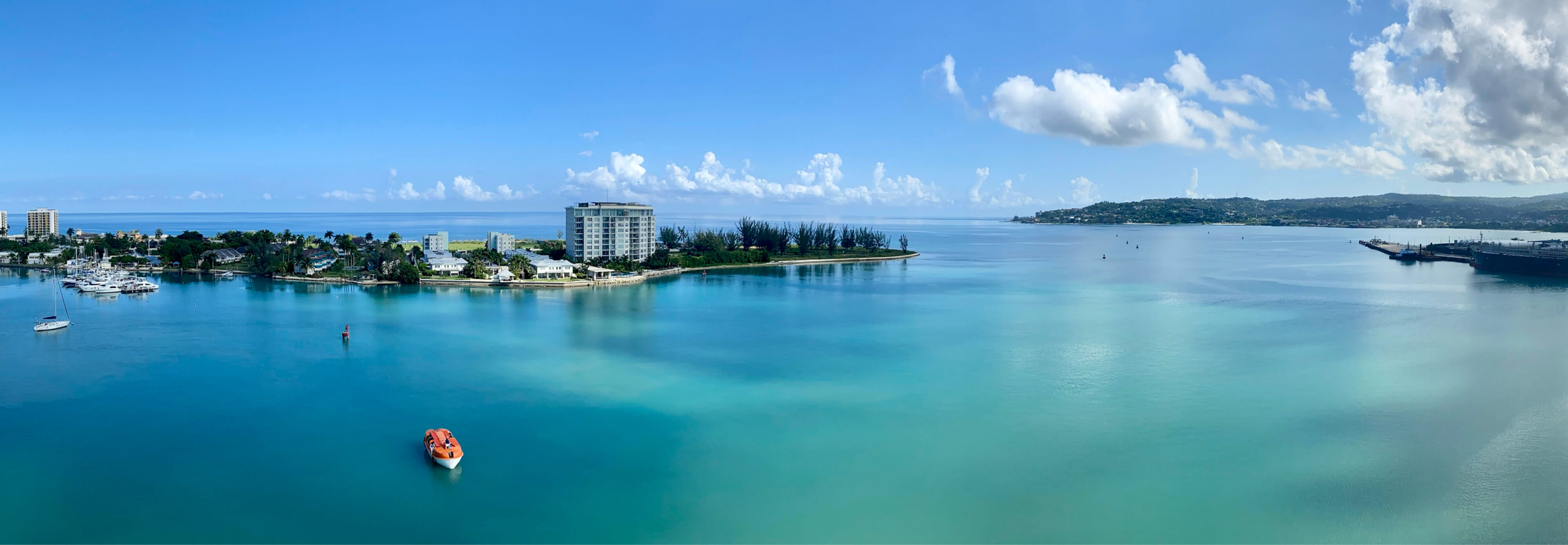 Lush island greenery and a ship sailing in the clear blue water in Jamaica