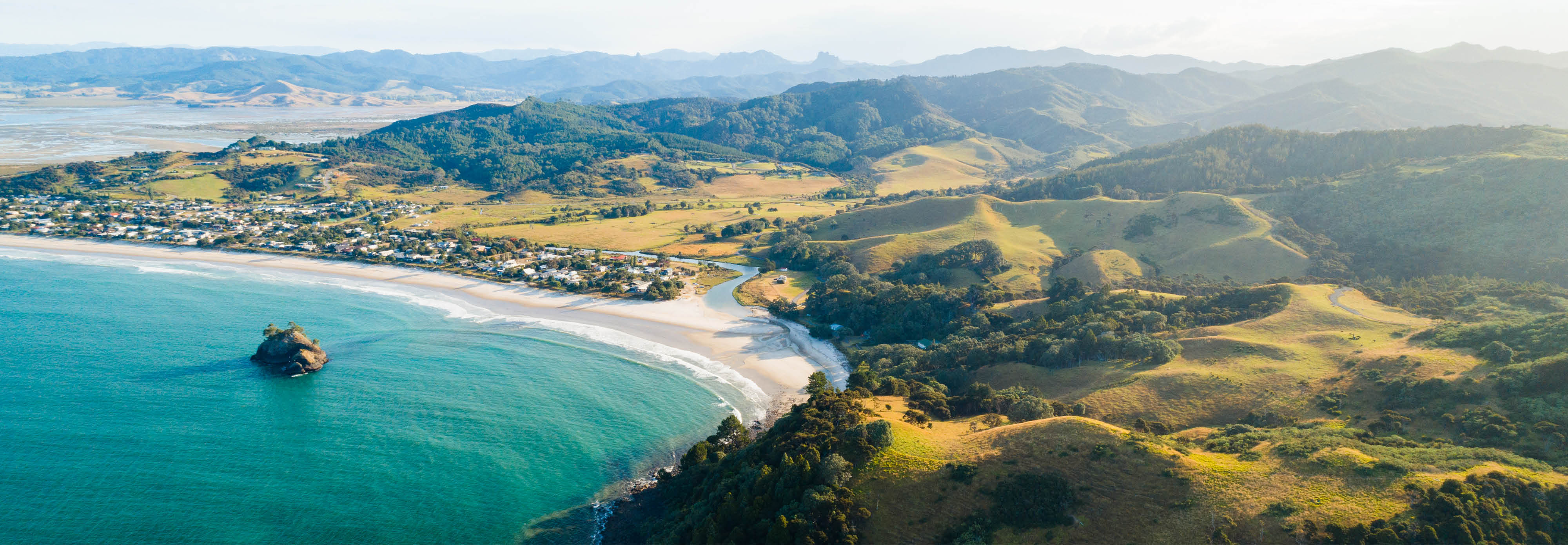 New Zealand's coastline, showcasing rugged cliffs and turquoise waters meeting sandy beaches