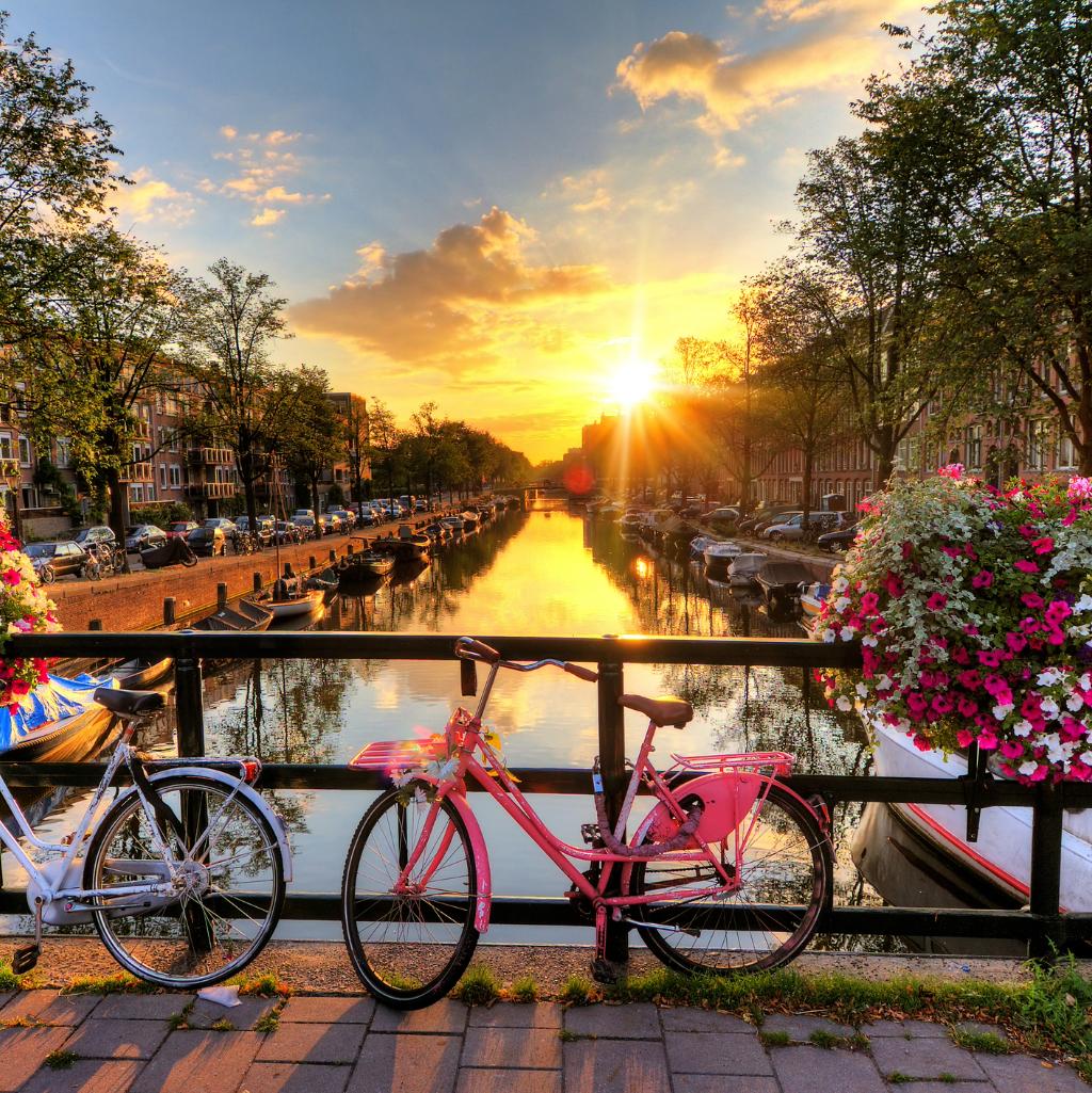 Bicycles on a bridge overlooking an Amsterdam canal at sunset