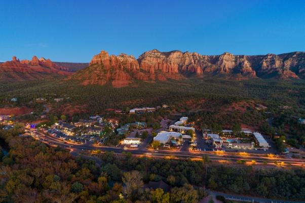 Town at sunset beneath red rock mountains and blue evening sky