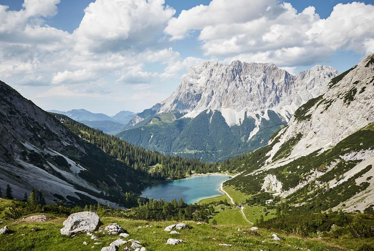 A tranquil lake surrounded by majestic mountains and vibrant green grass in Austria