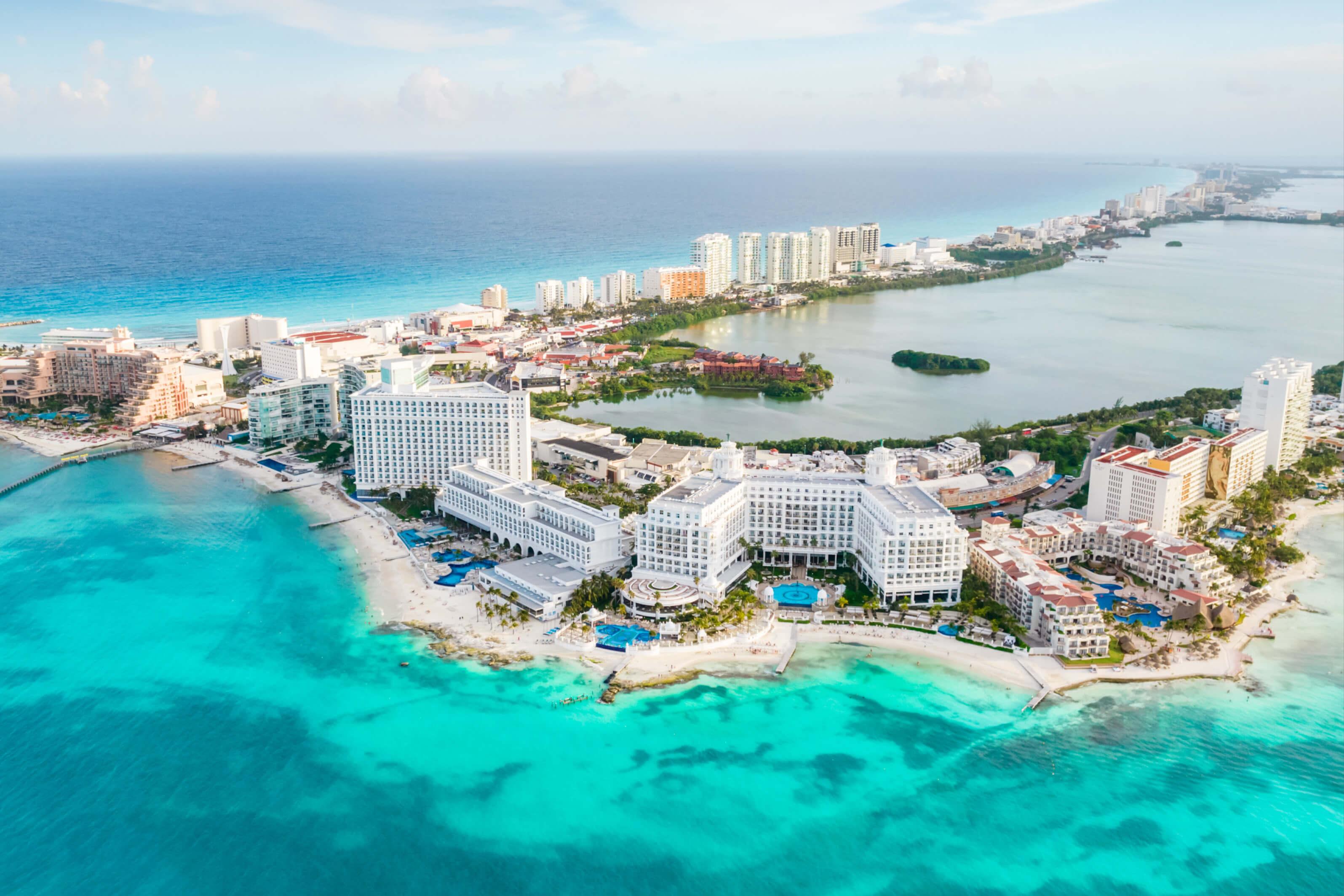 A stunning landscape of Cancun, Mexico, highlighting the coastline with resorts, palm trees, and inviting ocean waves