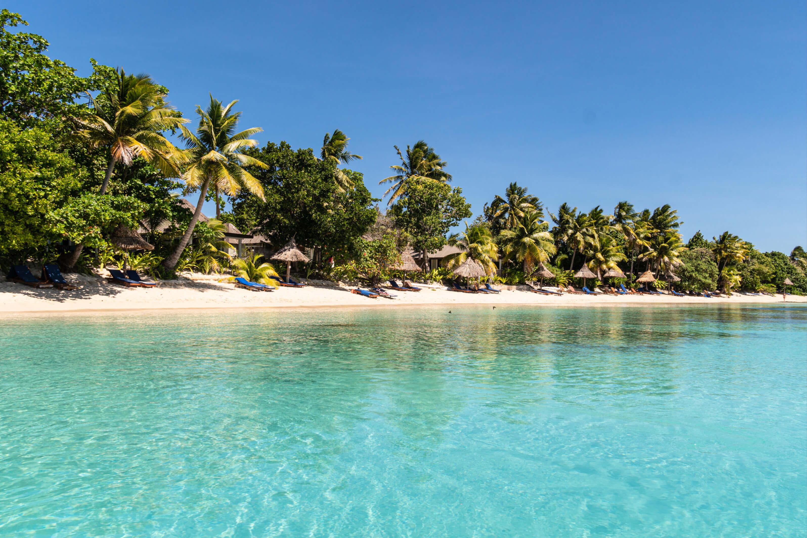 Clear blue water glistens under sunlight in Fiji, creating a serene and inviting atmosphere