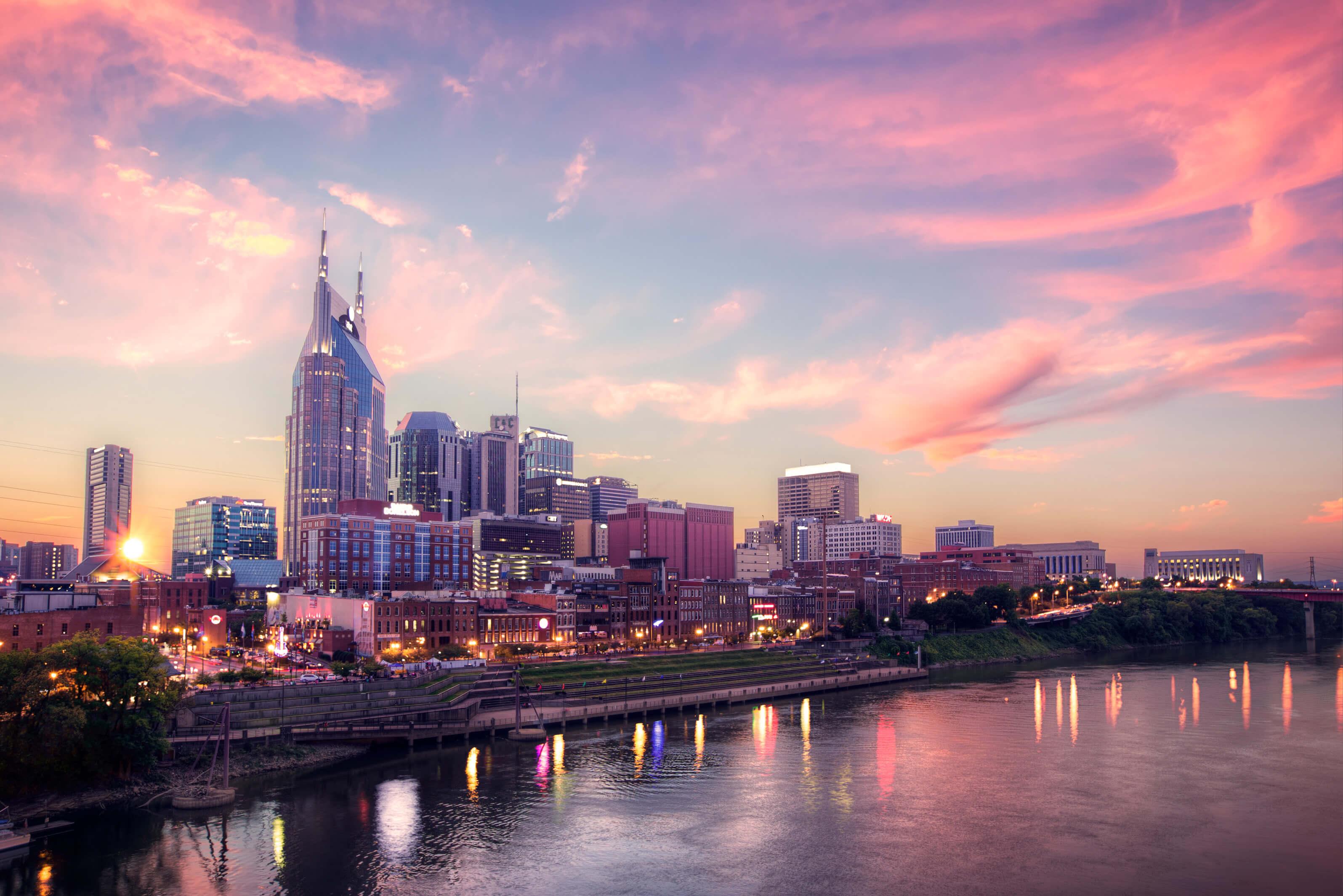 Nashville skyline silhouetted against a vibrant sunset, showcasing tall buildings and a colorful sky