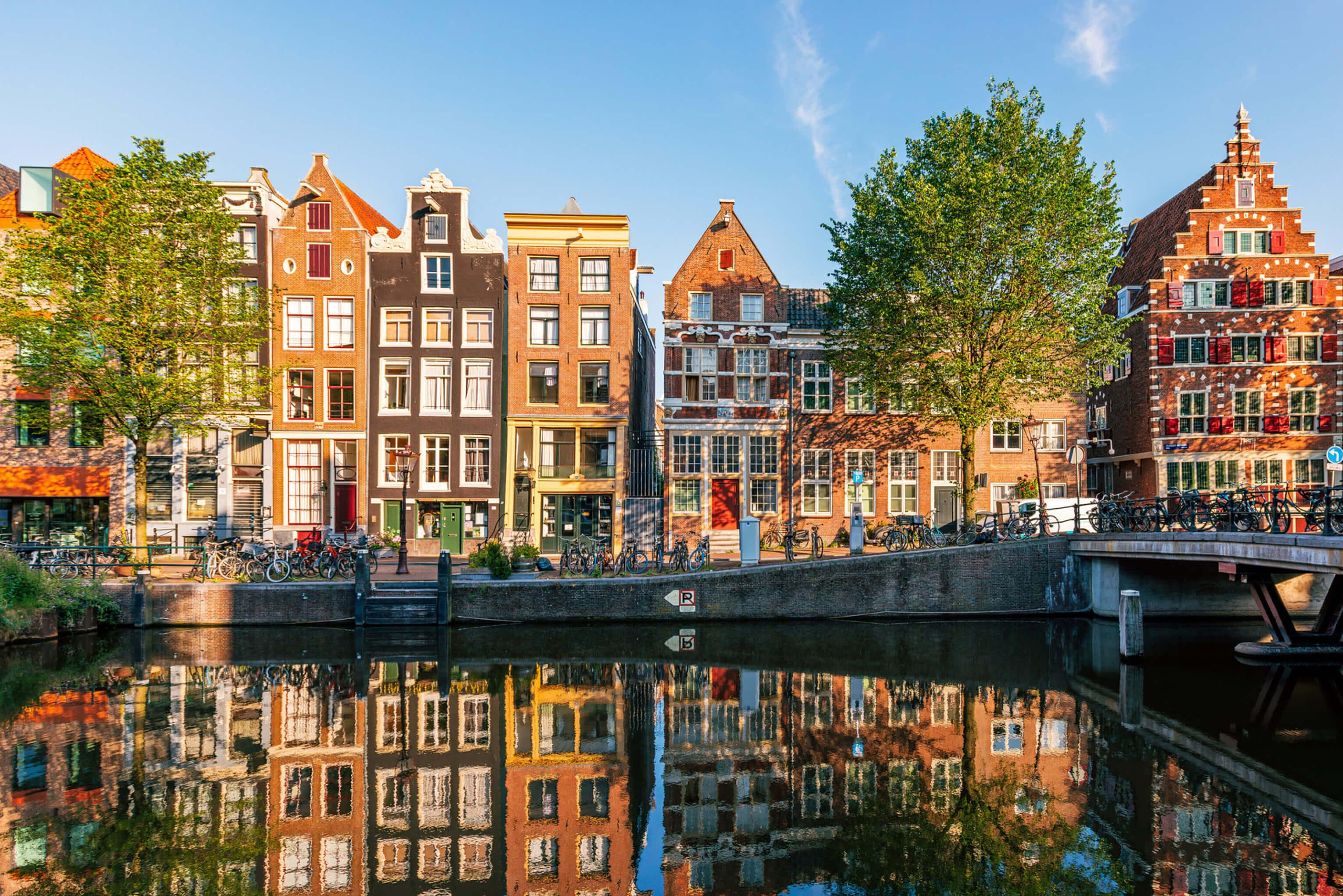 A picturesque canal in the Netherlands featuring a bridge, with various buildings lining the background