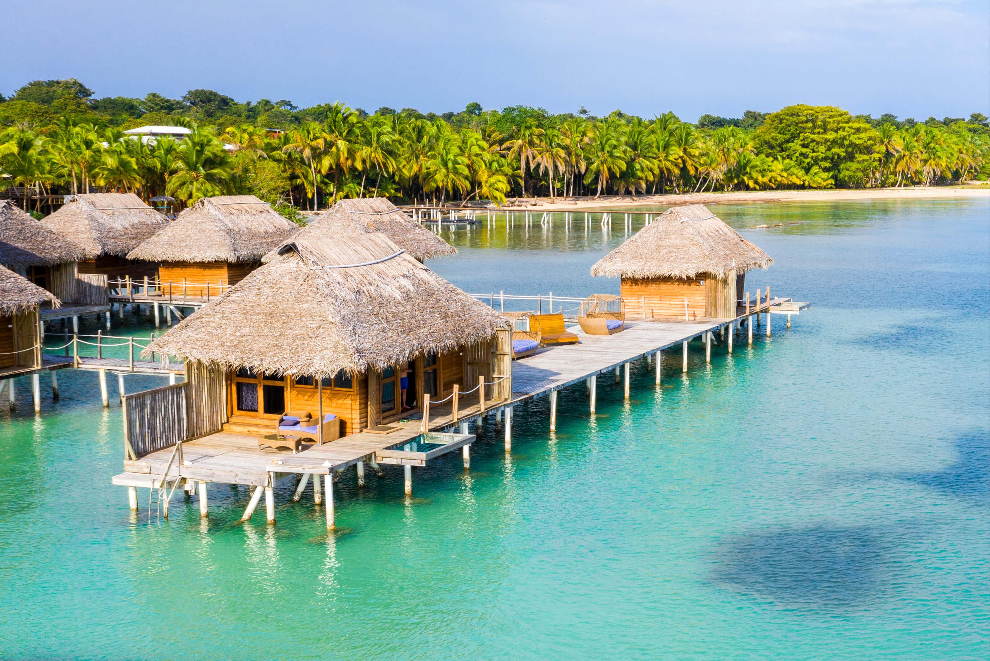 Thatched huts and a wooden dock extending into clear blue waters in Panama