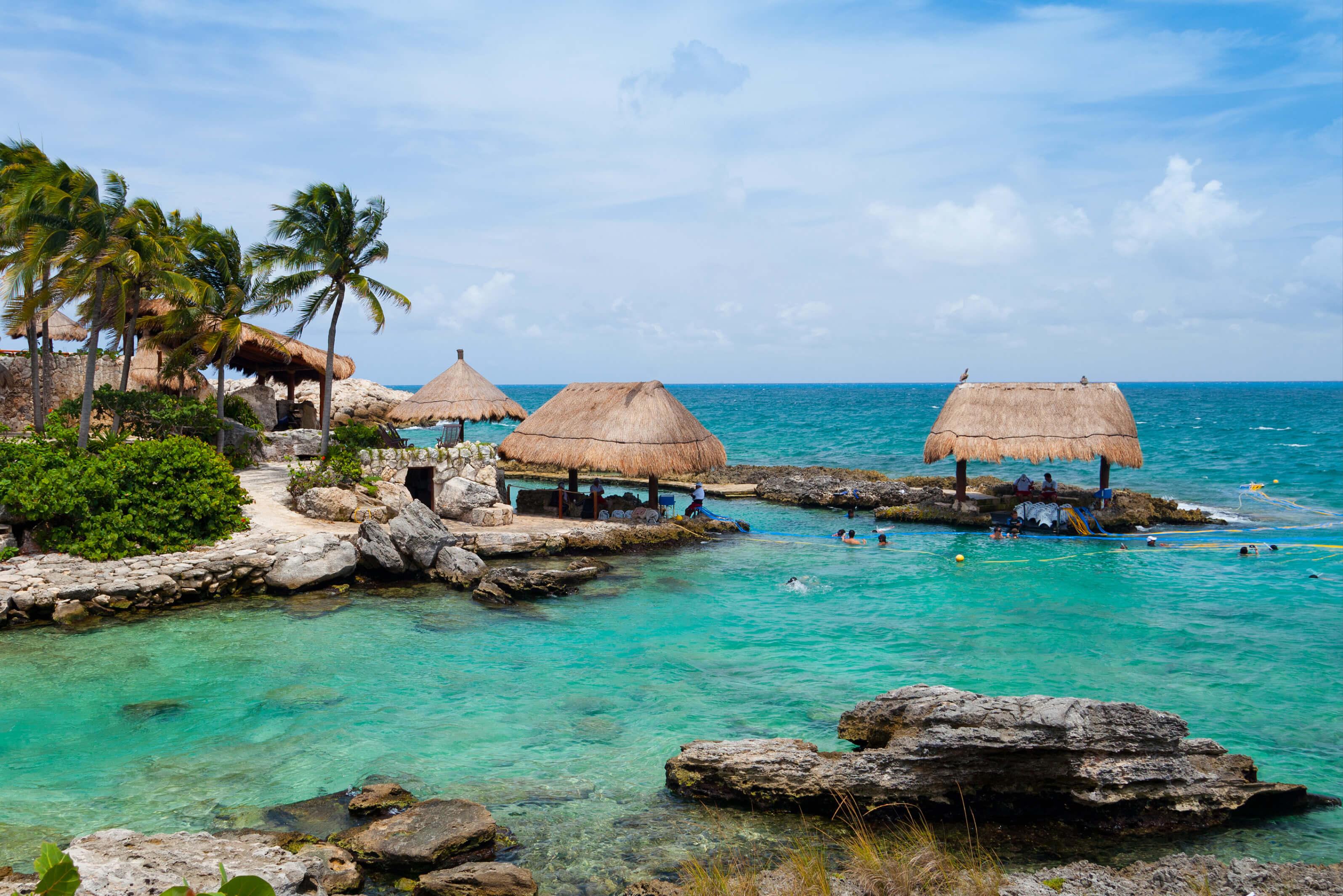 Beautiful ocean water with thatched huts and palm trees in Riviera Maya, Mexico 