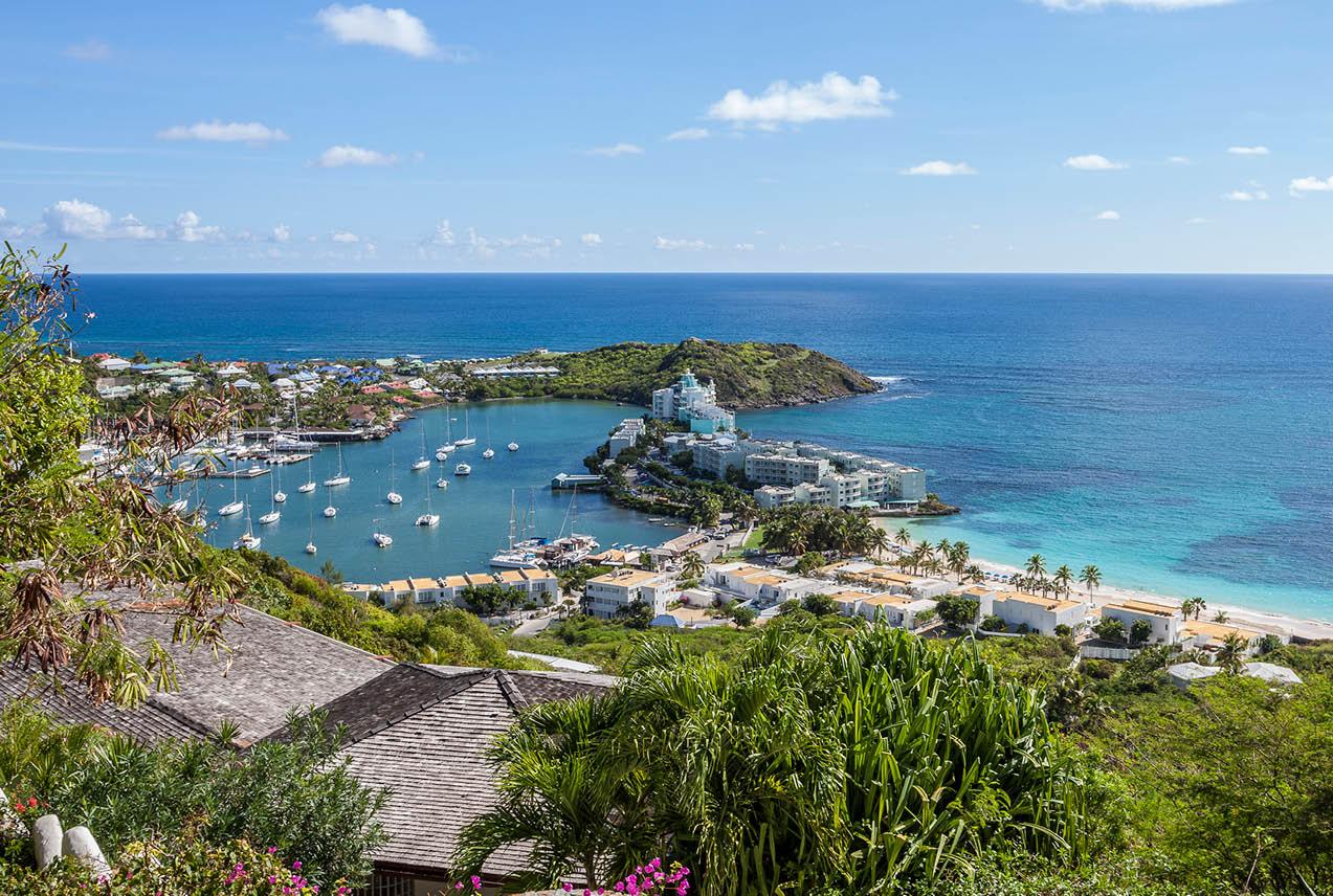 View of a bay in St. Martin with boats from a hillside, showcasing water and landscape under a clear sky