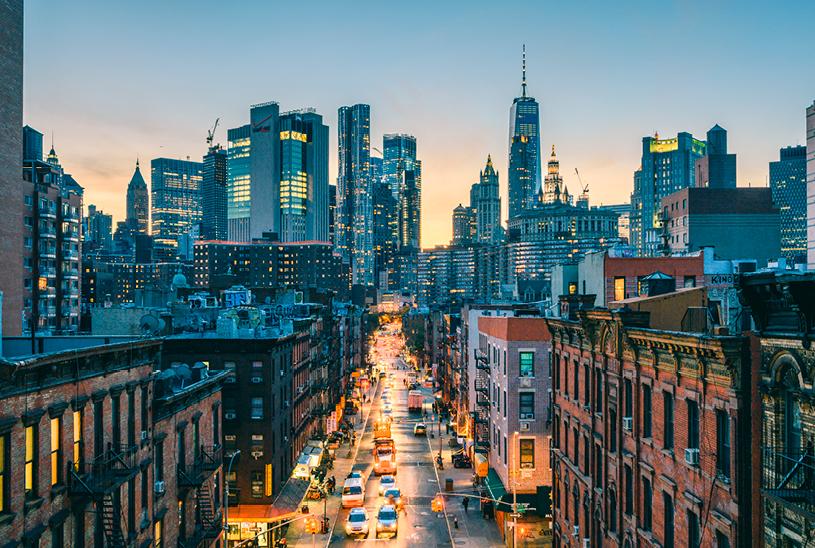 New York City skyline with a brightly lit bustling city street in foreground