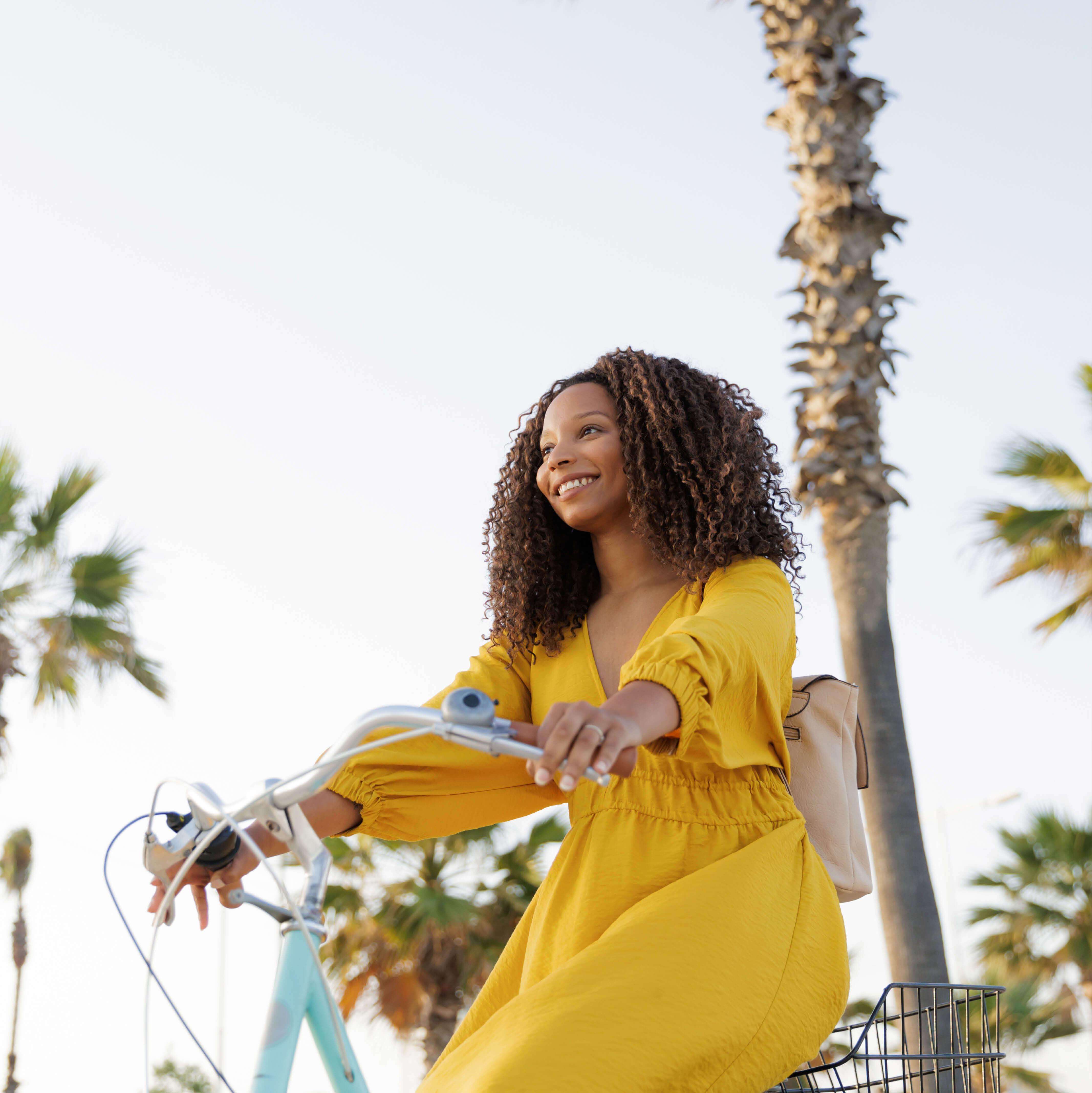 A woman in a yellow dress rides a bicycle in Grenada