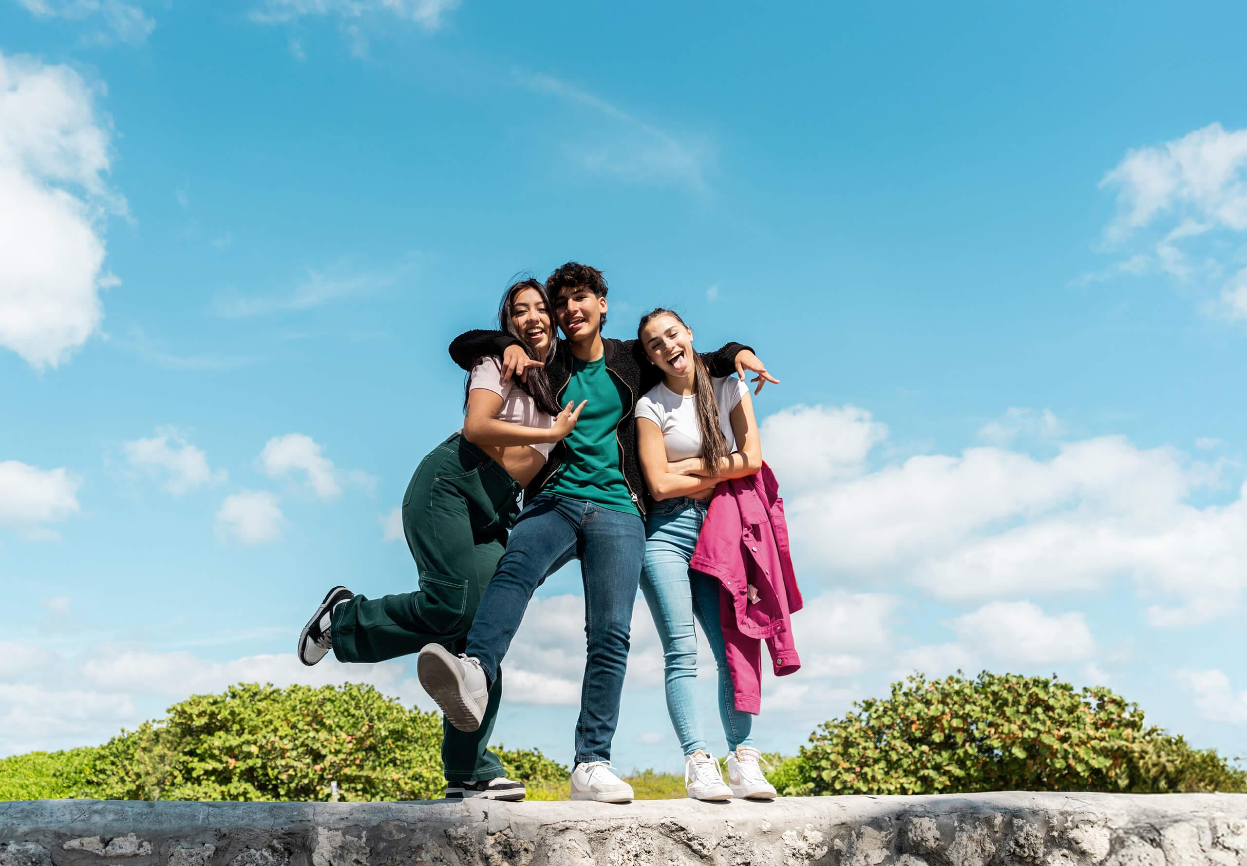 A trio of older student pose while on a group trip